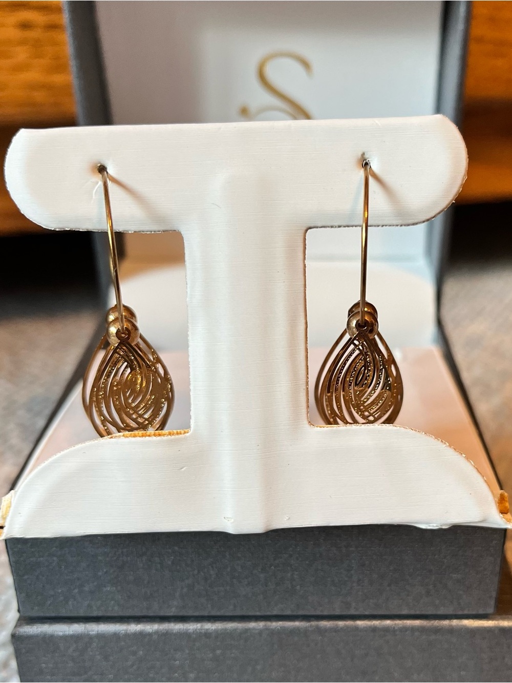 Delicate gold tone hoop earrings with tear drop detail